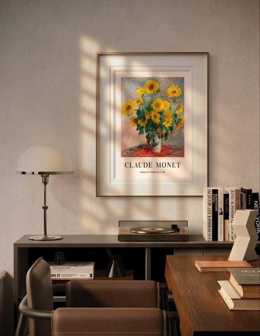 This framed Monet poster, "Bouquet of Sunflowers," hangs in a warmly lit, modern room, adding a touch of nature and elegance above a desk and shelves.