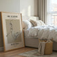 Framed artwork of a basketball player on a wall in a bedroom with a bed and basket.