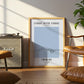 Framed artwork titled 'Stroke After Stroke Swimming' in a living room setting with a Marshall amplifier and brown chair.