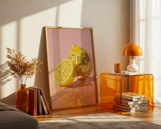 Modern interior with a decorative poster of a lemon and disco ball, orange table, and books.