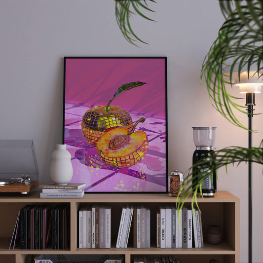 Framed artwork of a disco ball apple on a bookshelf with books and decor items.