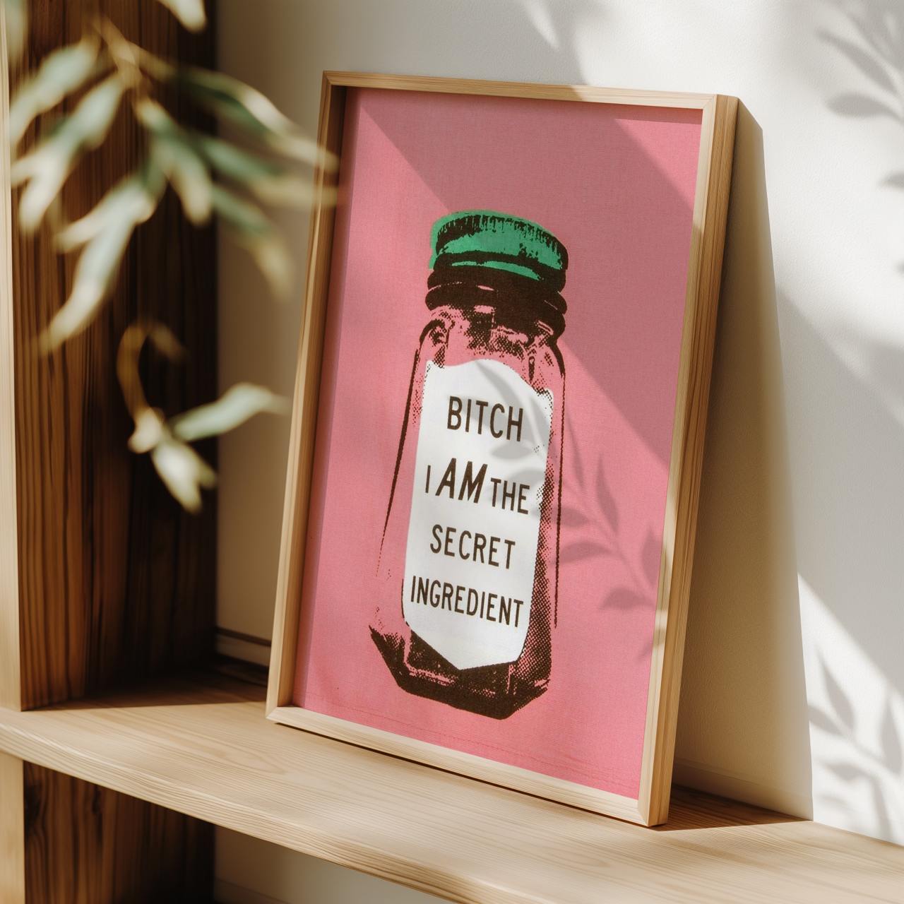 Framed artwork with a pink background and text on a wooden shelf.