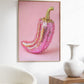 Framed artwork of a pink and gold pepper on a pink background, displayed in a room with a chair and vase.