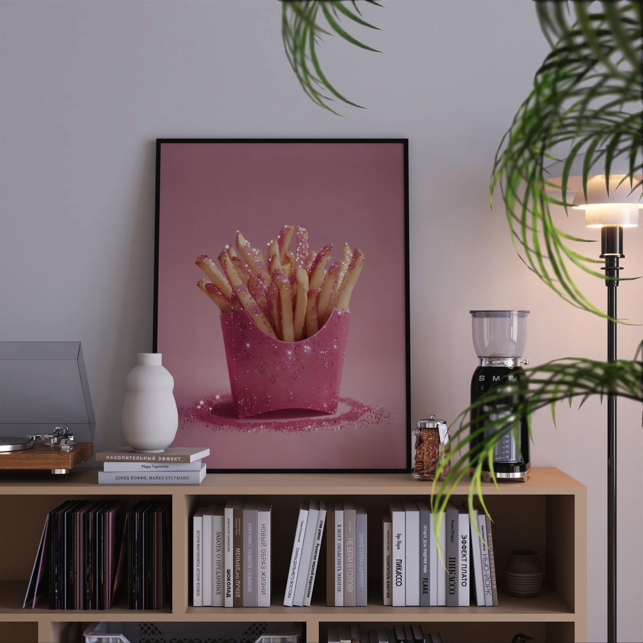 Framed artwork of pink fries on a bookshelf with decor items.