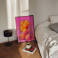 Framed artwork of oranges on a bedside table next to a bed