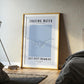 Framed poster titled 'Chasing Water' in a bedroom setting with a lamp and bed.