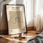 Framed poster of a basketball design on a wall next to a bed with a lamp and cup.