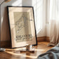 Framed artwork of a basketball player with text on a wooden floor next to a lamp and books.