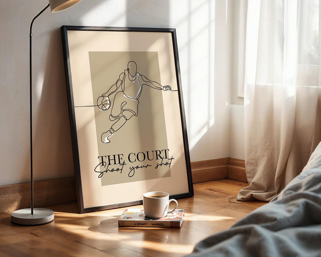 Framed artwork of a basketball player with text on a wooden floor next to a lamp and books.