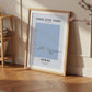 Framed artwork titled 'Stroke After Stroke' on a wooden floor with a bookshelf in the background.