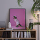 Framed artwork of a dinosaur in a robe on a bookshelf with books and decor items.