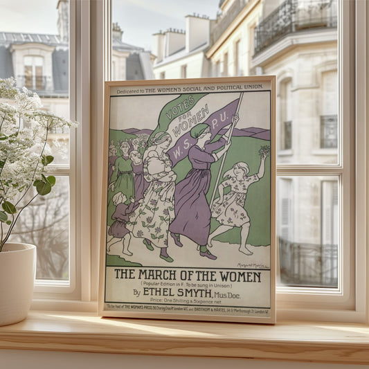 This image features a framed vintage poster titled “The March of the Women,” leaning against a wooden windowsill. The poster is displayed in a well-lit modern apartment