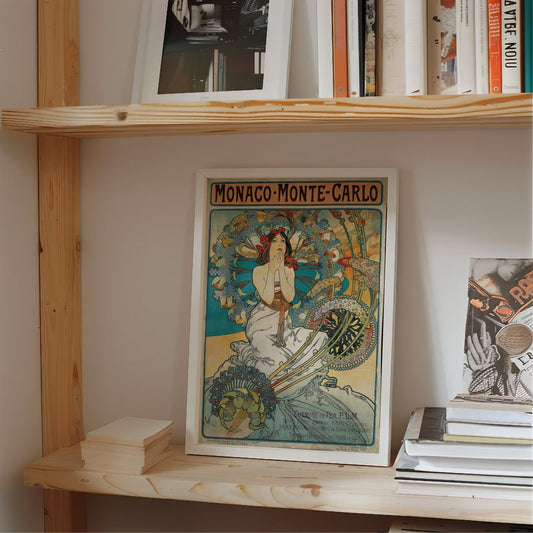 This image features a framed poster displayed on a windowsill, showcasing an elegant Art Nouveau-style artwork. The poster is an advertisement for 'Monaco-Monte-Carlo,' likely promoting travel to this famous location during the early 20th century