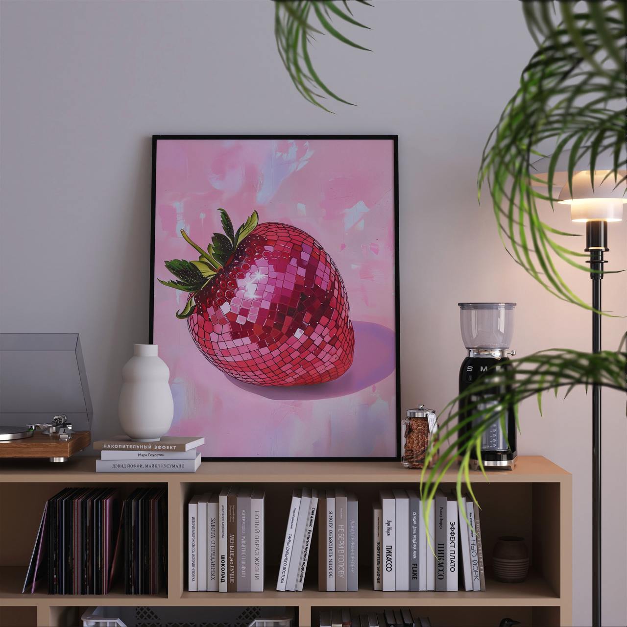 Framed artwork of a pink disco strawberry on a bookshelf with books and decor items.