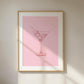 Framed artwork of a martini glass on a pink background