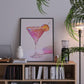 Framed artwork of a cocktail on a bookshelf with books and decor items.