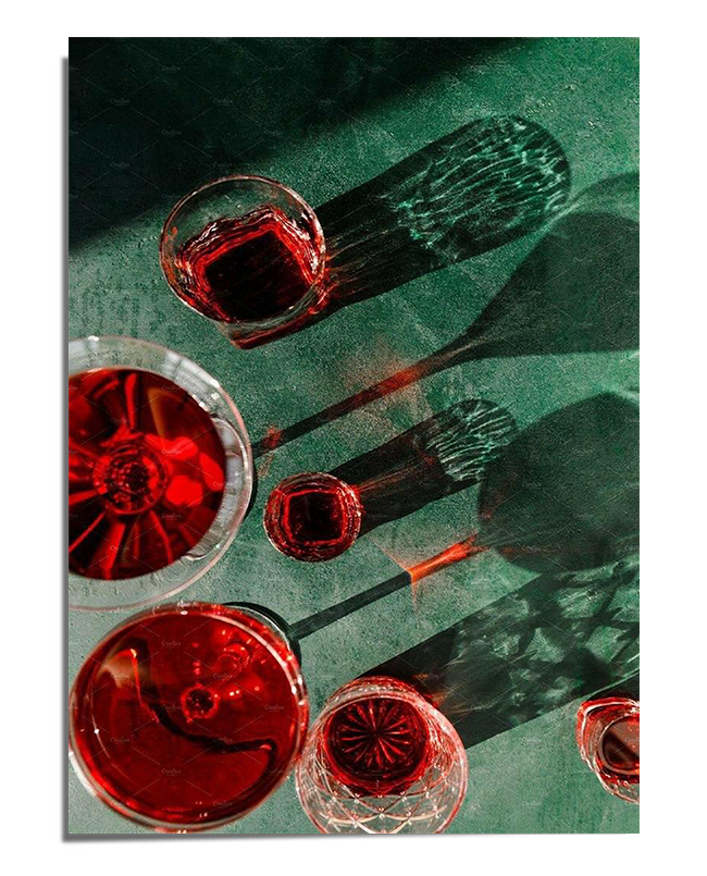 A collection of wine glasses filled with deep red liquid casting elongated shadows and reflections on a textured green surface. The interplay of light creates a dramatic and sophisticated visual effect.