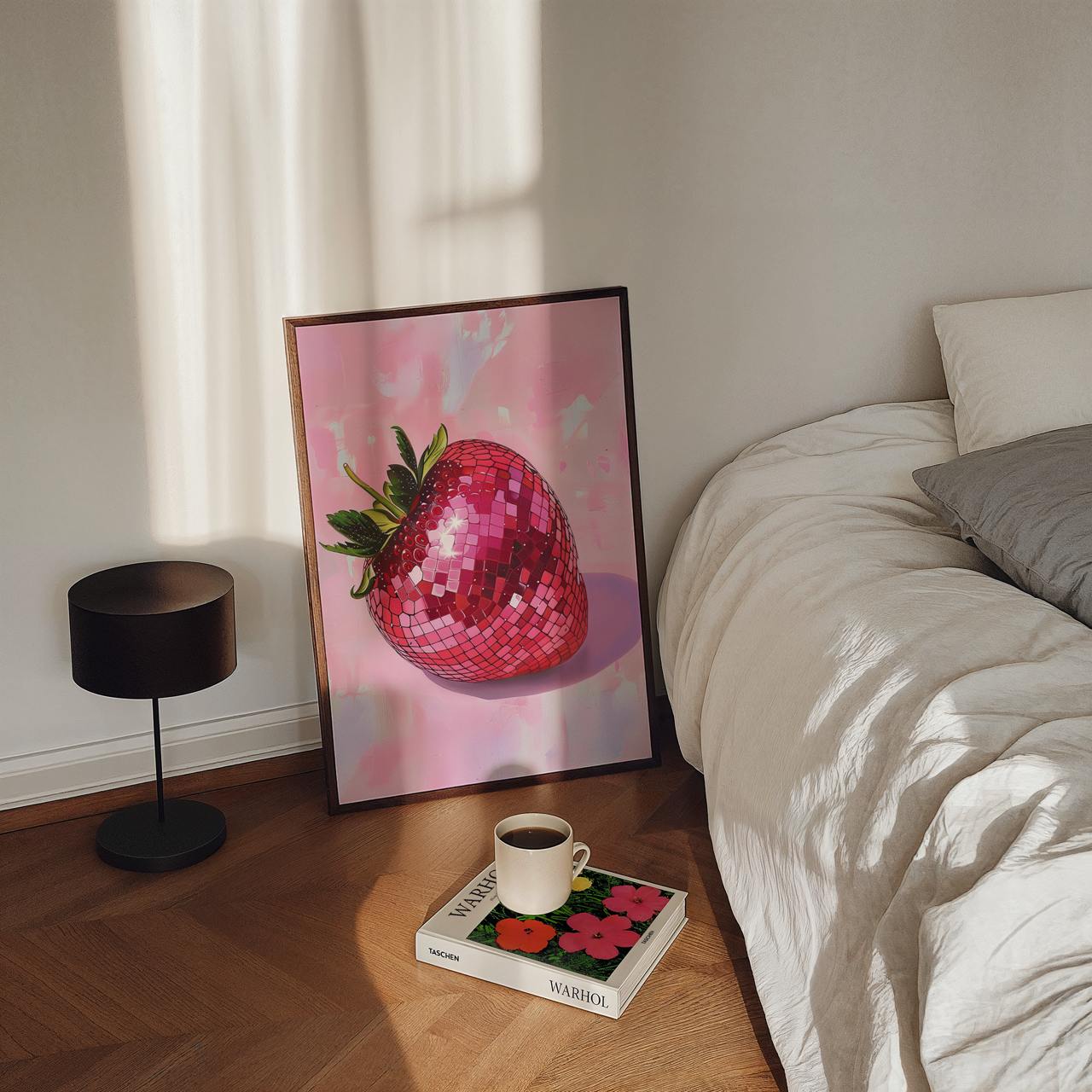 Framed artwork of a pink strawberry on a wooden floor next to a bed.