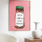 Framed artwork with a pink background and text on a wall above a white chair and wooden side table.