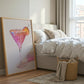 Bedroom with a bed, framed artwork of a cocktail, and a basket on the floor.
