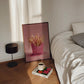 Framed picture of French fries on a bedside table next to a bed with a lamp and book.