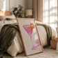 Framed artwork of a colorful cocktail on a bed in a cozy bedroom.